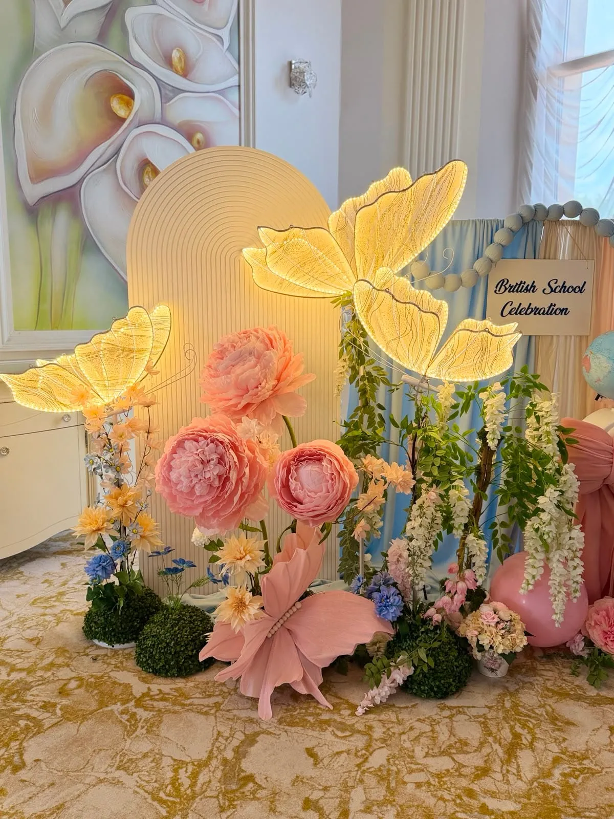 Arcadă cu fluturi luminoși și flori pastel pentru o serbare școlară